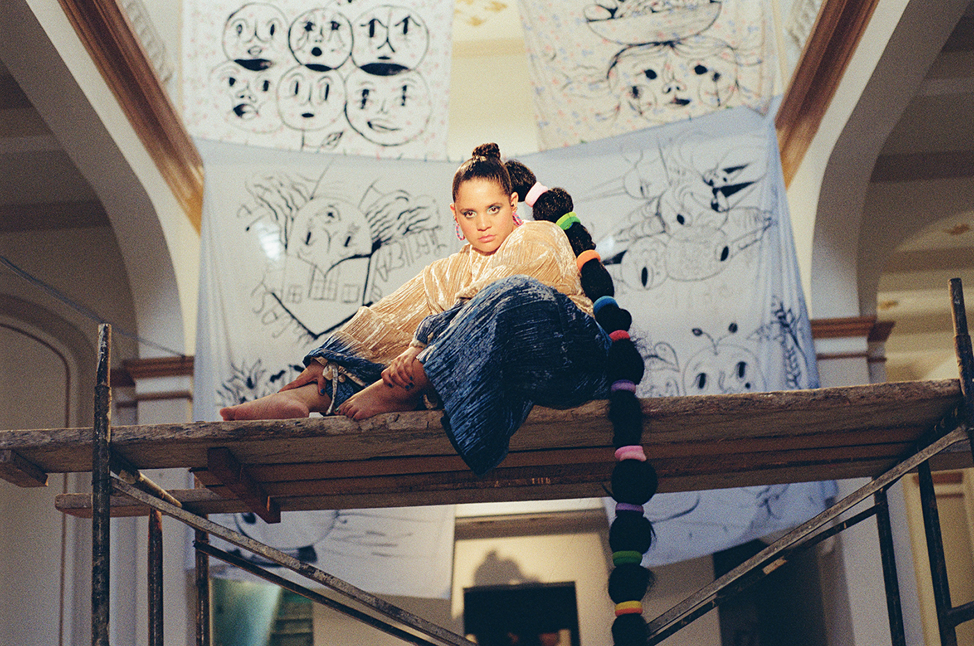 Lido Pimienta seated in front of black and white artworks